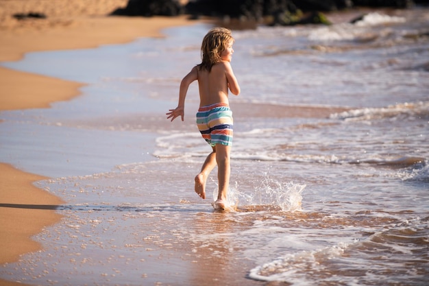 休暇中の夏の日に海の波に飛び散るアクティブな男の子ファミの概念