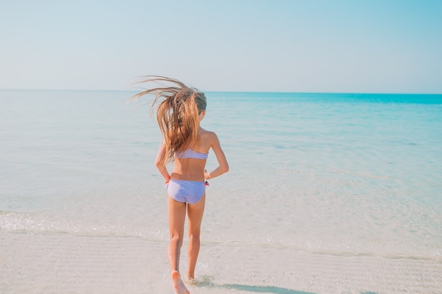 Active little girl on the beach having a lot of fun in shallow water