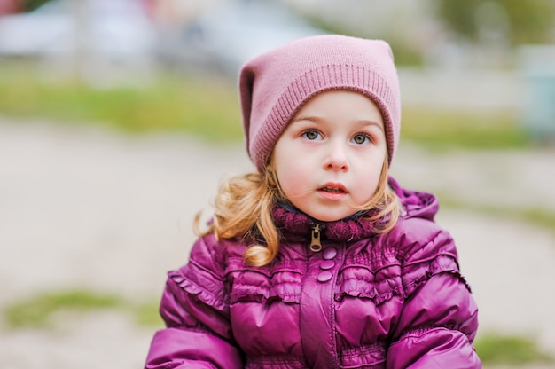 遊び場でアクティブな小さな女の子。遊び場の女の子の小さな子供。紫色のジャケットを着た子供