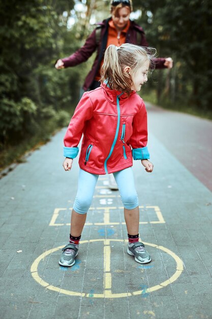 Active little girl playing hopscotch on playground outdoors jumping for joy