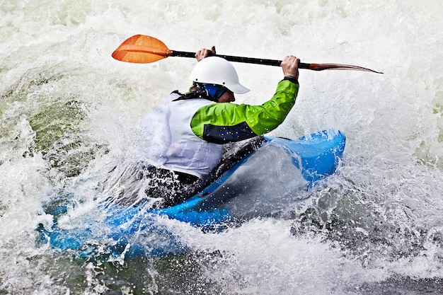 An active male kayaker rolling and surfing in rough water