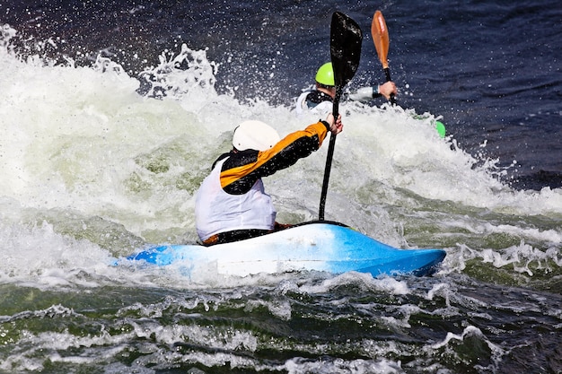 Un maschio attivo kayaker rotolamento e surf in acque agitate