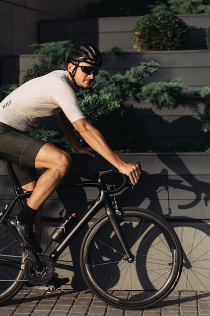 Active man in sport clothes practising in cycling during sunny day. Caucasian sportsman wearing safety helmet and glasses. Outdoors activity.