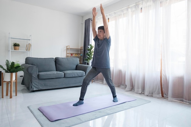 Active mature woman doing stretching exercise in living room at home