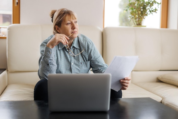 Active mature woman using a laptop for remote work from the home office Video conference video meeting Senior teacher leads webinar