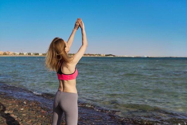 해변에서 운동을 하는 운동복을 입은 활동적인 중년 여성