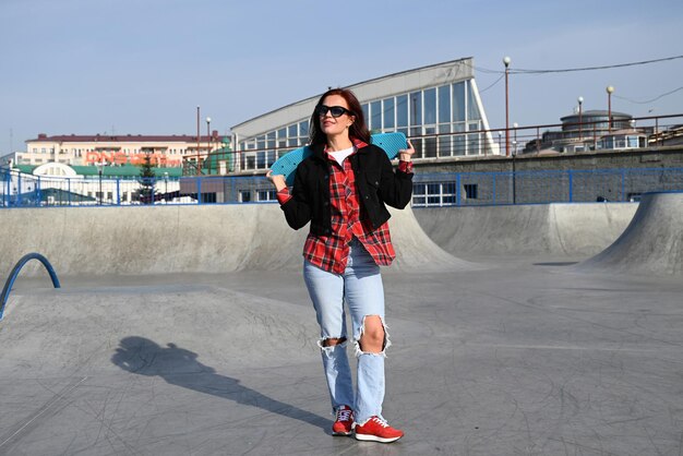 An active middleaged woman rides a skateboard on an empty road or highway An ordinary city woman relaxing on a skateboard after work The concept of a modern lifestyle