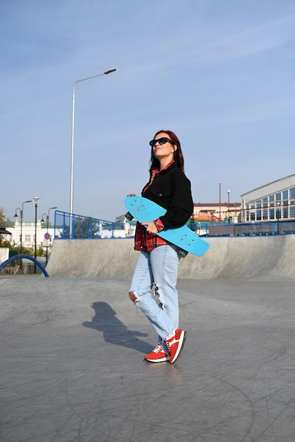 An active middleaged woman rides a skateboard on an empty road or highway An ordinary city woman relaxing on a skateboard after work The concept of a modern lifestyle