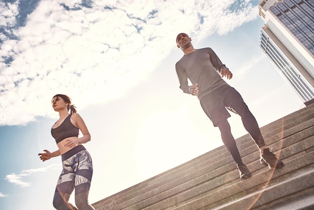 Active morning together young sports couple jogging down the stairs in the urban environment on