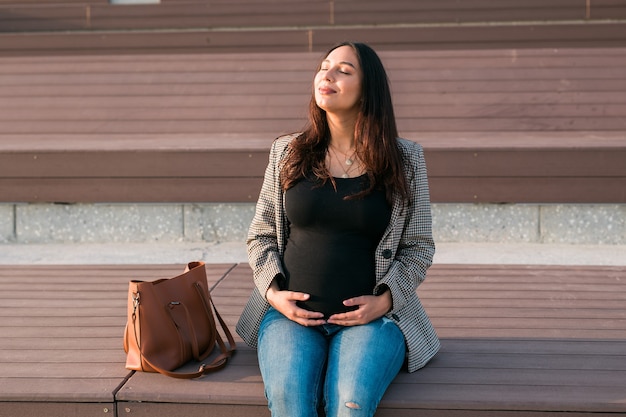 활동적인 임신 개념 행복한 젊은 비즈니스 또는 미래의 벤치에 앉아 있는 학생 임산부