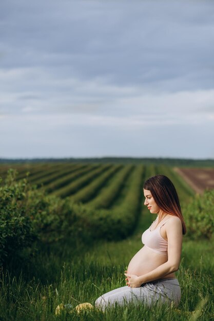 The active pregnant woman does sports exercises in a summer park