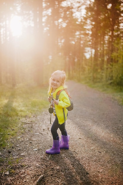 Active preschooler girl walking in the forest with backpack