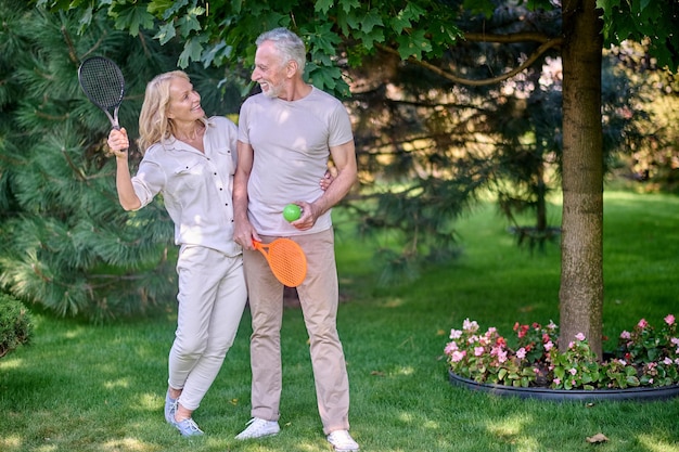 Active rest. mature mand and woman with rackets looking enjoyed and happy