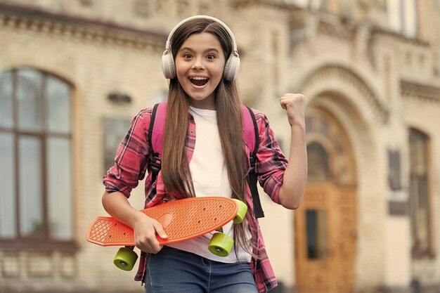 Active ride Happy girl skater flex arm holding penny board outdoors Action sport Recreational activity Healthy lifestyle Street skateboarding Summer vacation Active and energetic