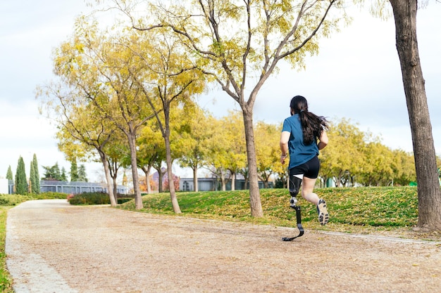 Active runner with a hightech carbon fiber prosthetic leg jogs among fall foliage