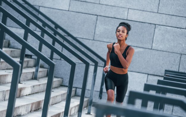 アクティブなランナースポーツ服を着た若いアフリカ系アメリカ人女性は、日中に屋外でトレーニングをしています