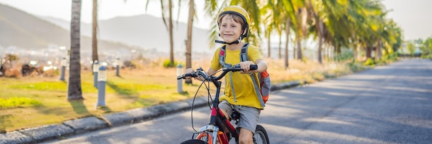 Active school kid boy in safety helmet riding a bike with backpack on sunny day happy child biking