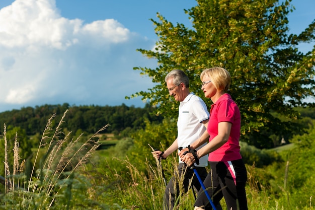 Active senior couple hiking with Nordic walking poles
