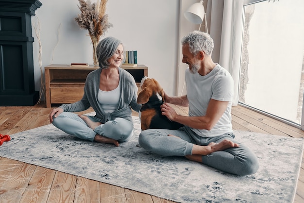 Photo active senior couple in sports clothing exercising and smiling while spending time at home