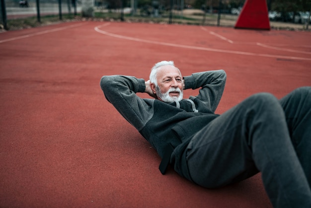 Active senior doing sit-ups outdoors.