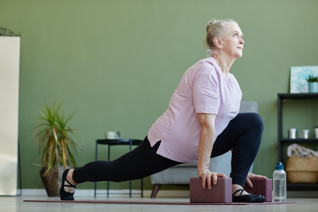Photo active senior female with yoga blocks exercising on the floor