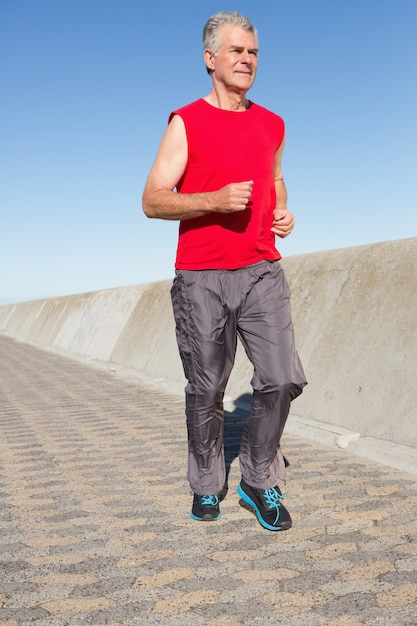 Active senior man jogging on the pier