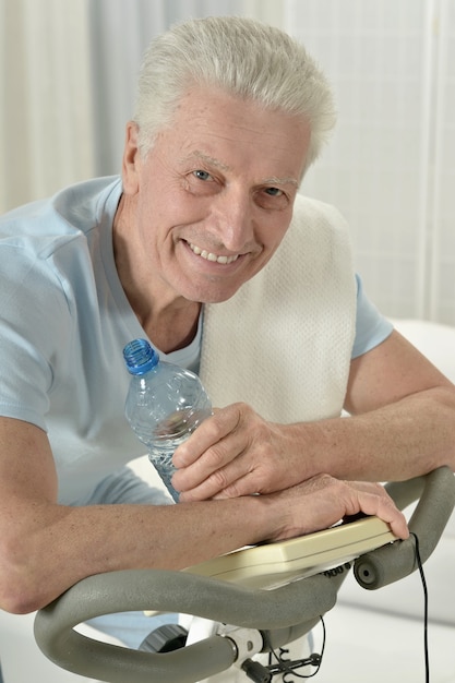 Active senior man with bike in gym