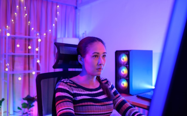 An active and serious young woman gamer on his powerful personal computer playing