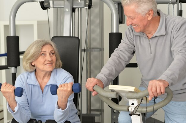 Active smiling senior couple exercising in gym