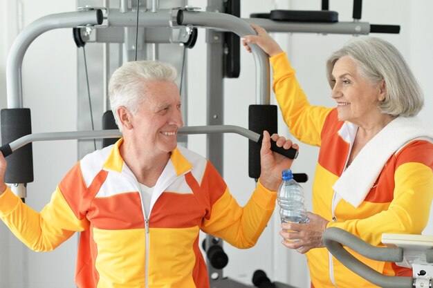 Активная улыбающаяся старшая пара, тренирующаяся в тренажерном зале
