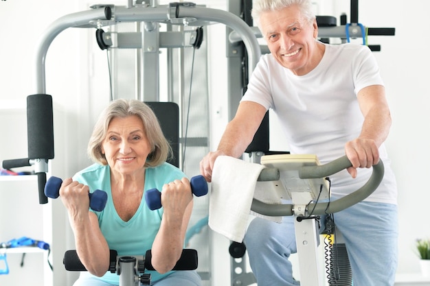 Active smiling senior couple exercising in gym