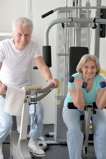 Photo active smiling senior couple exercising in gym