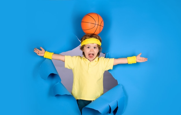 Stile di vita sportivo attivo piccolo giocatore di basket sorpreso bambino tiene la palla sulla testa attività per bambini