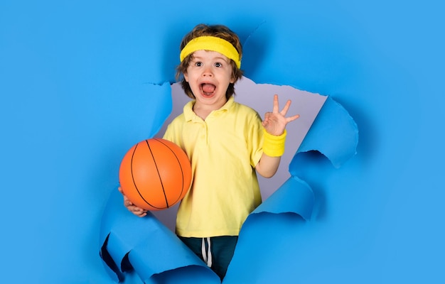 Active sport lifestyle surprised child boy with basketball ball shows ok sign basketball training