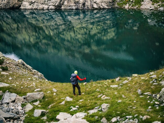 山の湖の水の背景でバックパックとアクティブな観光客