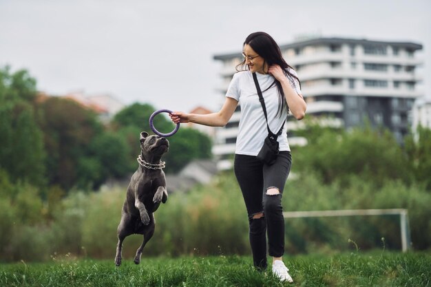 Active weekend time spending Young brunette is having a walk with her dog outdoors