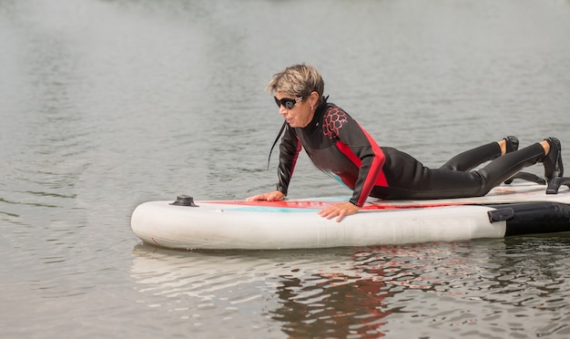 サーフィンでウェットスーツの水泳で65年のアクティブな女性