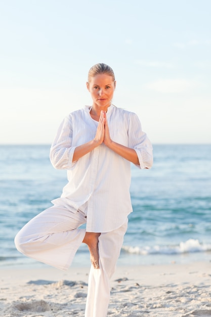 Donna attiva praticando yoga sulla spiaggia