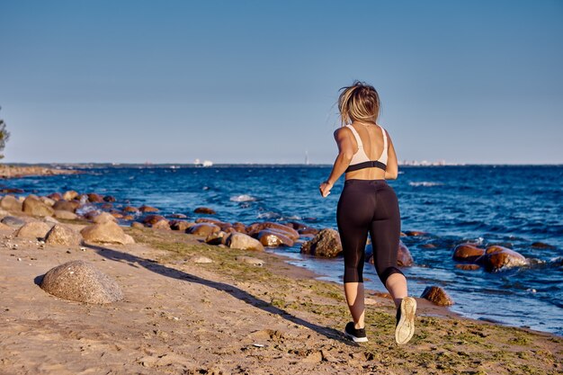 Active woman runs near shore at summer day