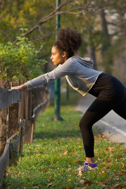 Foto donna attiva che allunga i suoi muscoli all'aperto