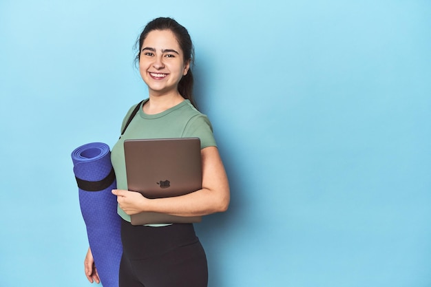 Active woman with a mat and computer ready for a virtual workout