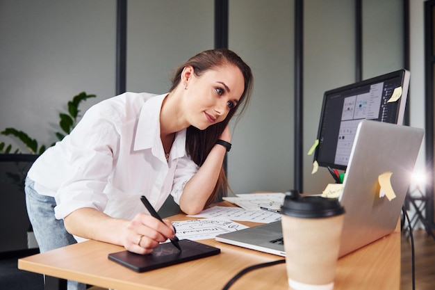 Active working Young adult woman in formal clothes is indoors in the office