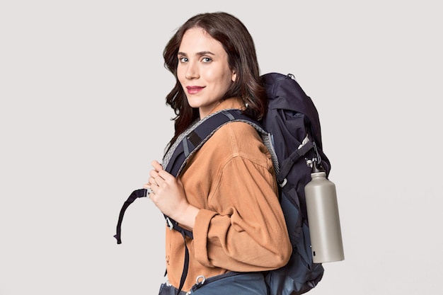 Photo active young caucasian woman with hiking backpack in studio