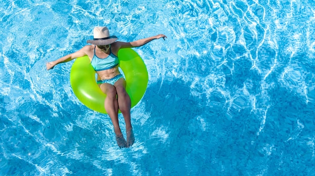 Active young girl in swimming pool aerial drone view from above teenager relaxes and swims on ring