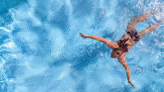 Active young girl in swimming pool aerial drone view from above young woman swims in blue water