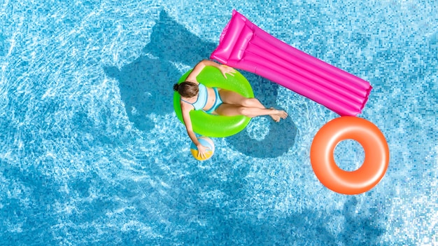 Active young girl in swimming pool aerial top view from above child swims on inflatable ring