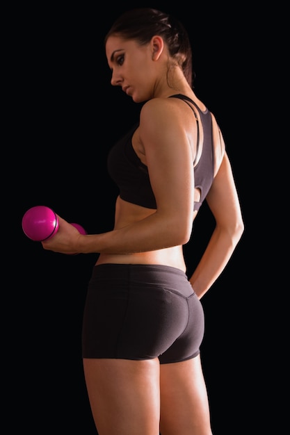 Active young woman lifting a pink dumbbell 