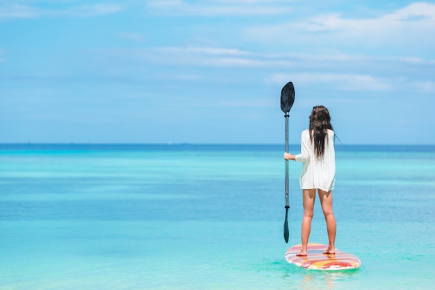 Active young woman on stand up paddle board