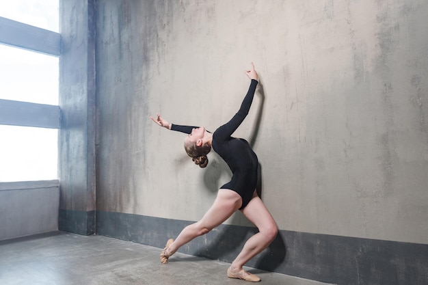 Activity instructor training in dancing near gray wall and window. Studio shot