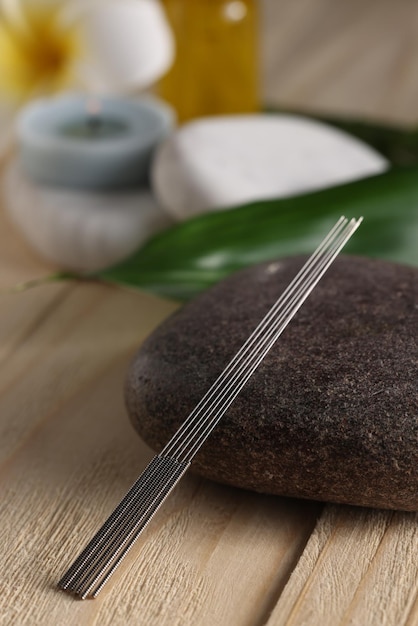 Photo acupuncture needles and spa stone on wooden table